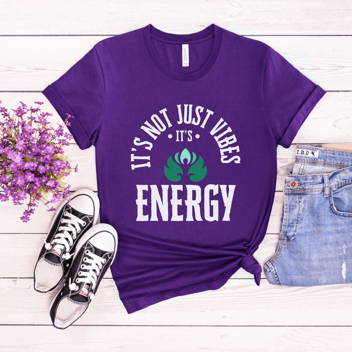 Purple t-shirt with 'It's not just vibes, it's energy' text on a wooden surface with sneakers and flowers – Lunar Lightwear conscious clothing