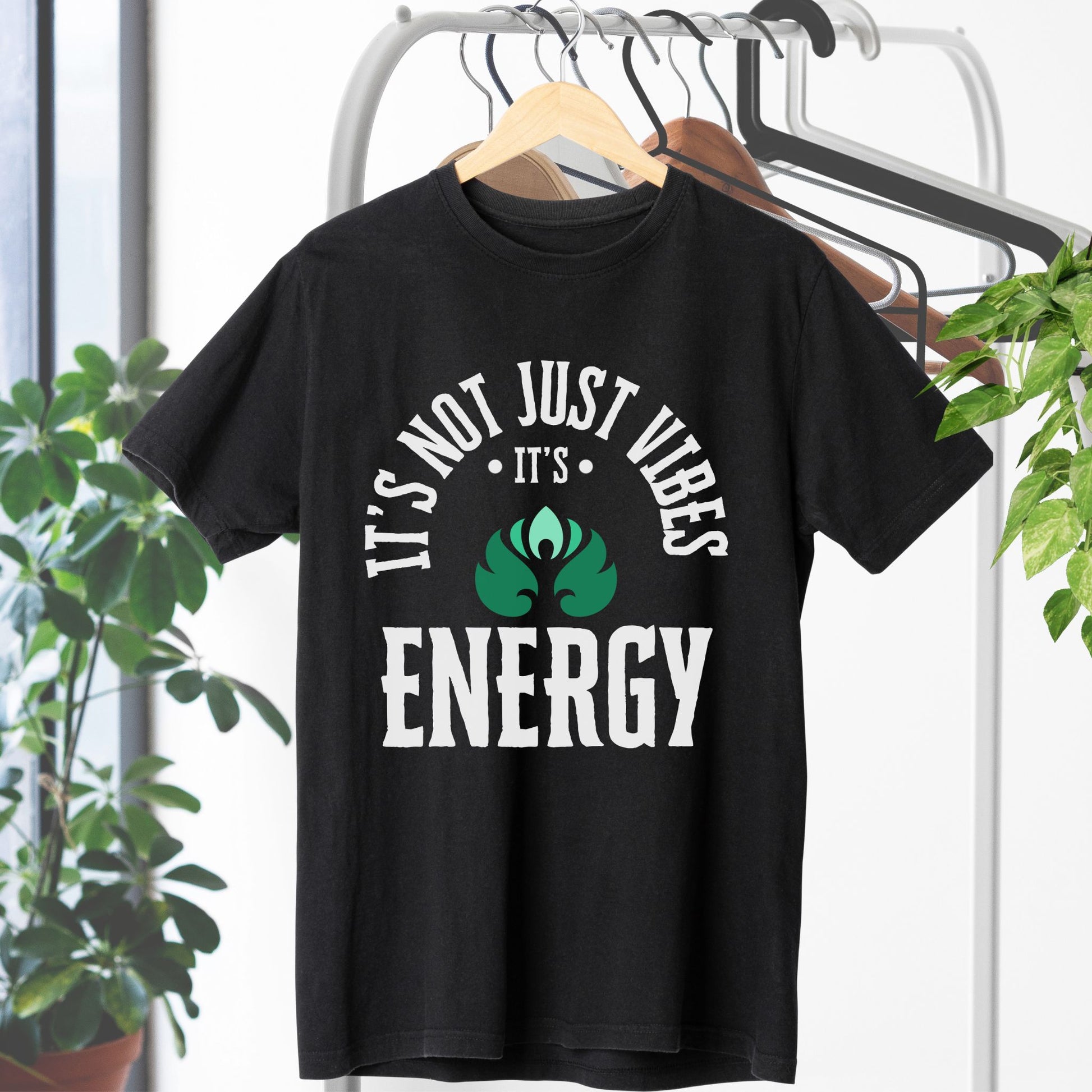 Black t-shirt with 'It's not just vibes, it's energy' text on a hanger with plants in the background – Lunar Lightwear conscious clothing